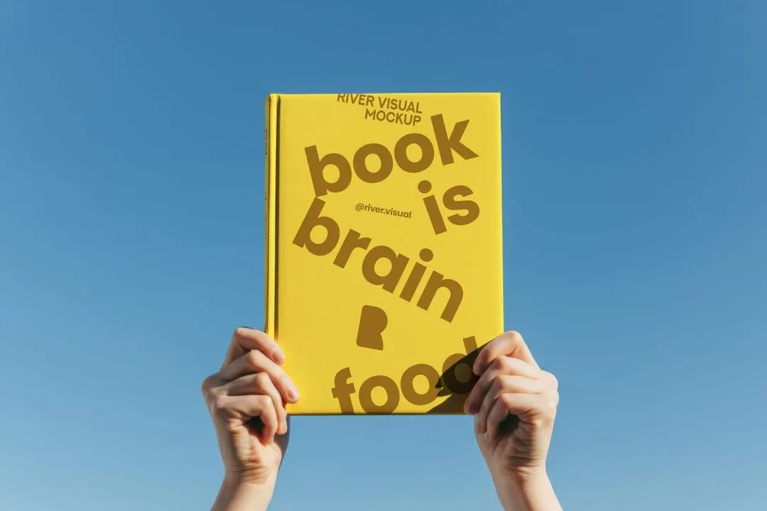 A person holding up a book that says book is brain food.
